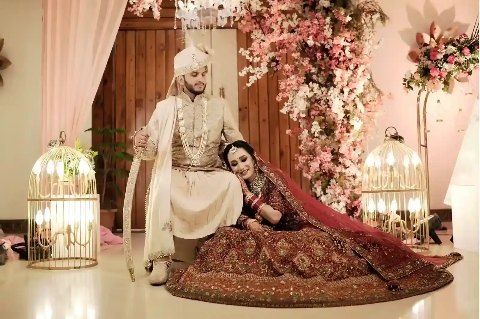 Bride and groom in traditional South Asian wedding attire posing amid floral decor